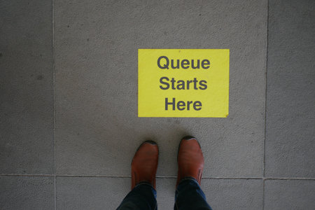 Queue starts here sign on the floor with boots belowの写真素材