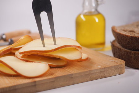 Slicing cheese on a wooden board with olive oil nearbyの写真素材