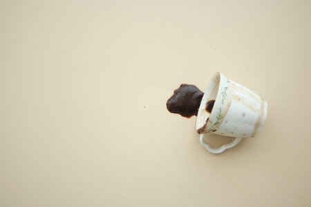 Coffee spills from a white cup on a plain surfaceの写真素材