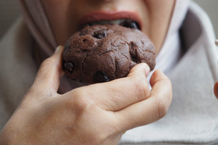 Eating a chocolate cookie during a snack timeの写真素材