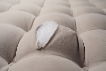 Damaged mattress with exposed filling on soft fabricの写真素材