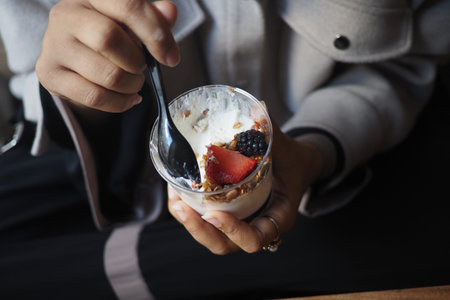 Enjoying yogurt with fruits and granola in a cafeの写真素材