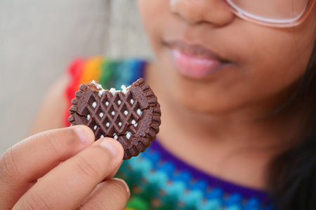 Girl holding a chocolate cookie with a bite taken outの写真素材
