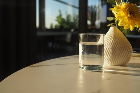 Glass and vase on marble table in sunlightの写真素材