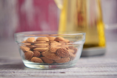 Bowl of almonds next to bottle of oil on wooden tableの写真素材
