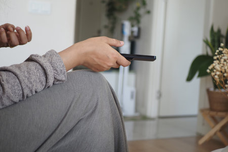 Person sitting and holding a remote control at home