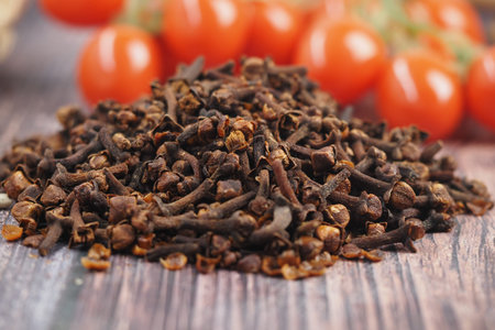 Cloves on wooden table, cherry tomatoes behindの写真素材