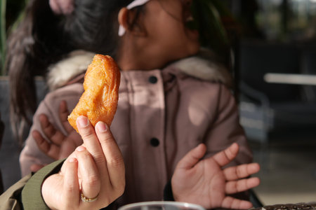 Child enjoys snack while seated at indoor cafeの写真素材