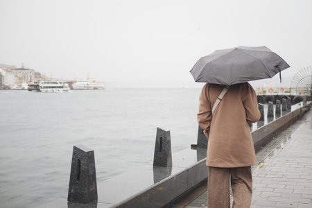 Walking by the water with an umbrella on a rainy dayの写真素材