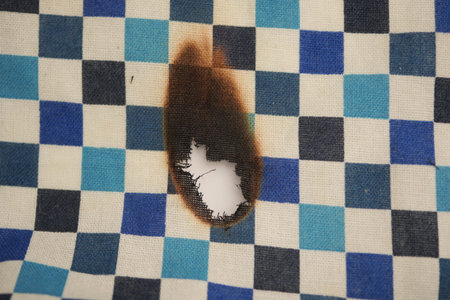 Burn mark on checkered cloth located on a tableの写真素材