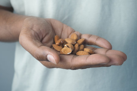 Hand holding almonds in a casual setting with soft lightingの写真素材