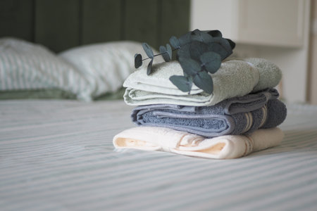 Soft towels are stacked on a bed with green sheetsの写真素材