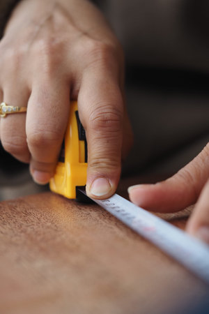 Measuring wood with a tape measure in a workshop
