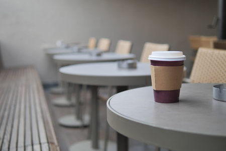 Coffee cup on table in outdoor seating area at cafe