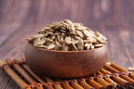 Sunflower seeds in a wooden bowl on a bamboo matの写真素材