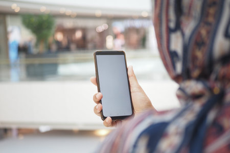Person holds smartphone in shopping mall during the day