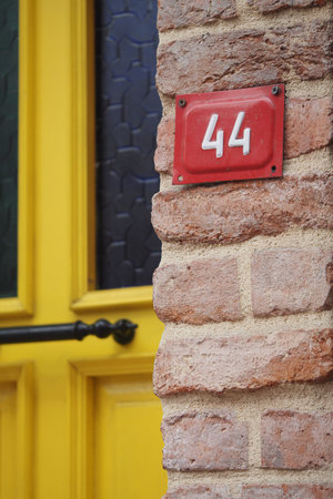 House number displayed on a brick wall near a yellow door