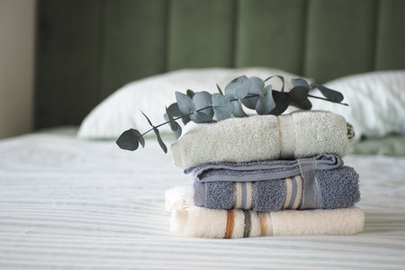 Freshly folded towels on a bed with green backgroundの写真素材