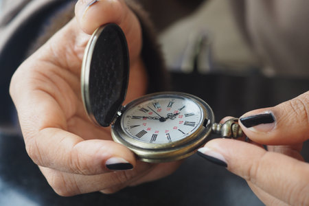 Holding a pocket watch in hands while checking the time