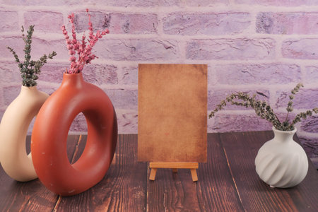 Vases with dried flowers and a blank canvas on a table