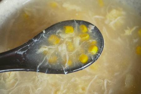 Soup with corn is served in a black ladle
