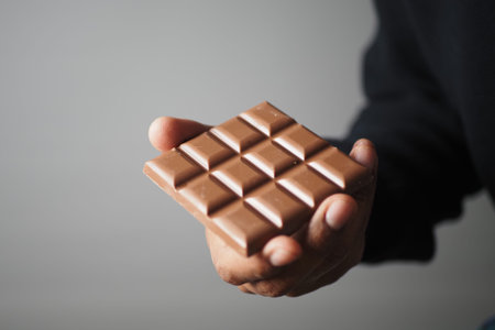 Hand holds a chocolate bar with squares ready to eat