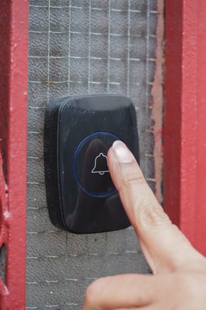 Person presses doorbell at a house entrance