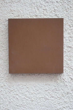 Brown rectangular board on a textured wall outside