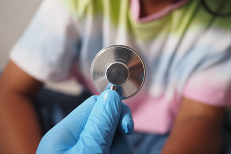 Gloved hand holding a stethoscope in a clinic