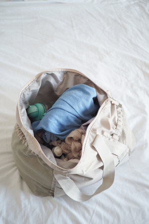Bag with clothes and toys on white bed