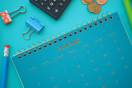 Calendar and office supplies on a blue table in Januaryの写真素材