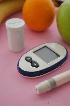Diabetes management tools and fruits on pink surface