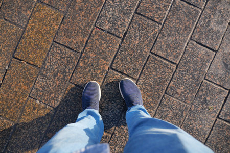Person stands on stone pathway with blue shoes