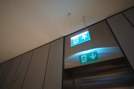Exit signs point upward and downward in a building hallway