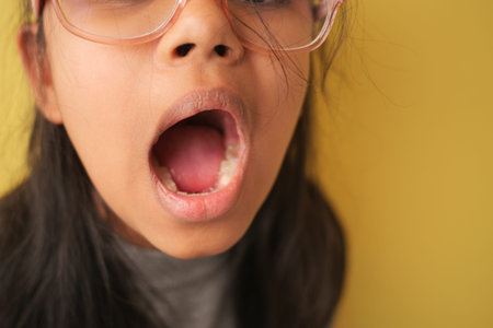 Girl yawning in front of a yellow wall