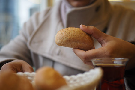 Holding a bun while sitting at a table with tea
