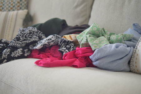 Clothes stacked on a couch in a living roomの写真素材