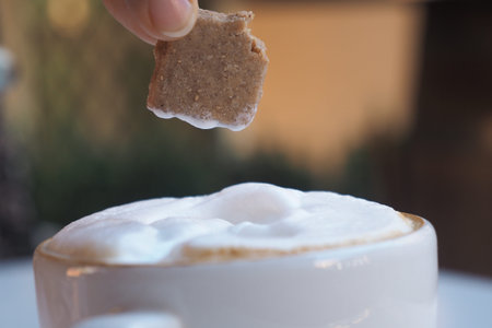 Dipping a piece of biscuit into a cup of coffeeの写真素材