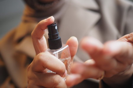 Hand sprays hand sanitizer from a clear bottle in a close view
