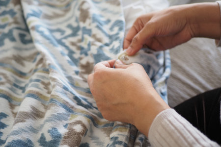 Hands sewing a fabric piece at home in the afternoon