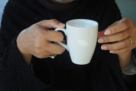 Holding a white cup of drink in a casual setting