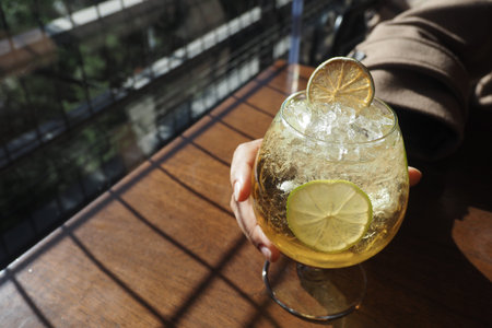 Fresh drink with lime slice in a glass near window