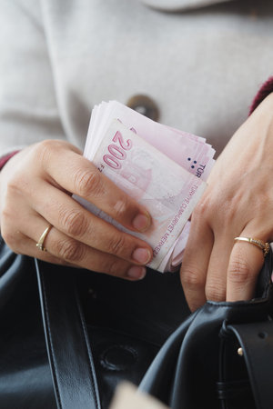 Counting turkish lira money while holding a bag in a public place