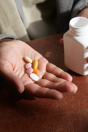 Holding various pills in hand while sitting at a table