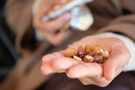 Person holds a mix of nuts in their hand at a gatheringの写真素材