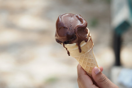 Holding a chocolate ice cream cone on a sunny day