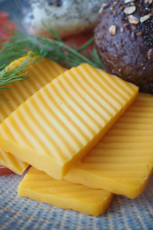 Blocks of yellow cheese on a wooden board with herbs