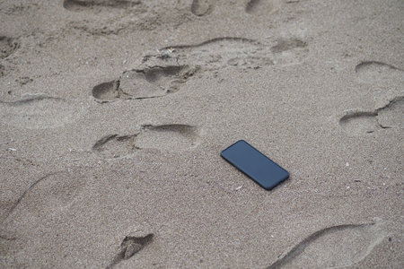 Smartphone on sandy beach. lost smart phone conceptの写真素材