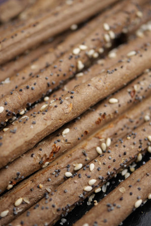 Baked breadsticks with seeds on a dark tray