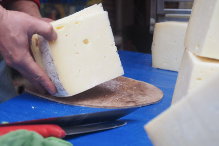 Cheese maker cutting blocks of cheese in a local market